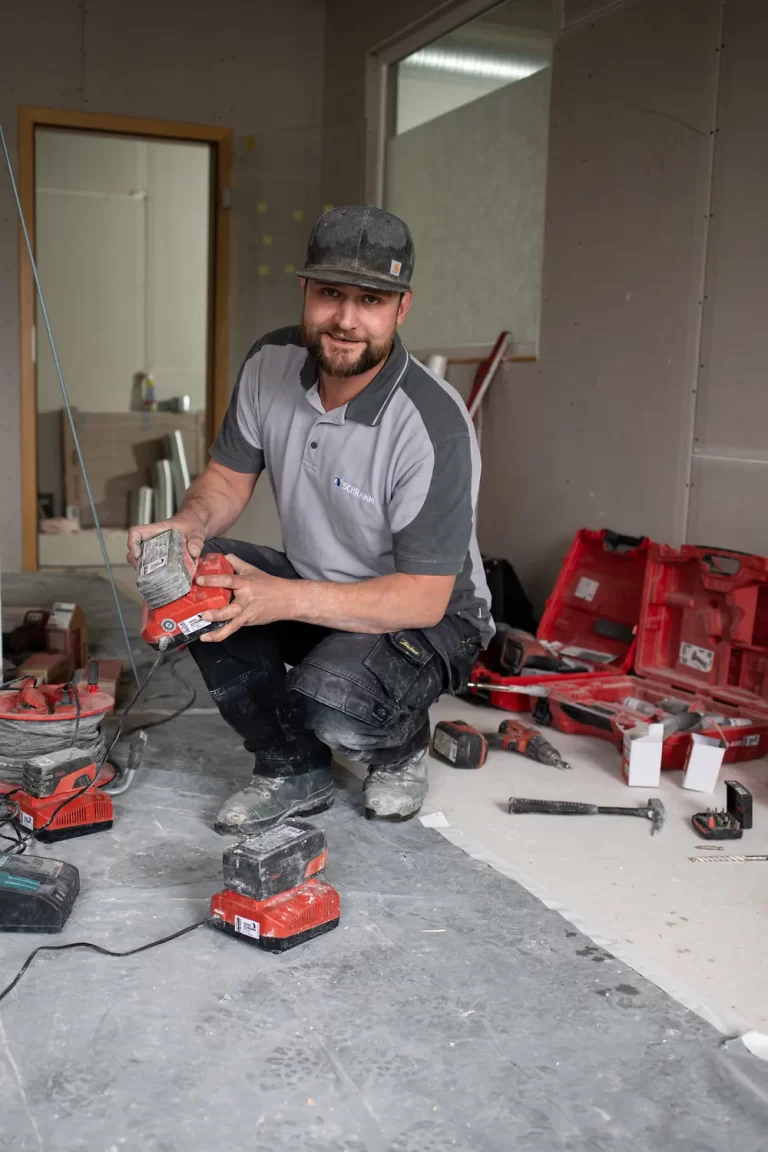Handwerker mit Akkuwerkzeug auf Baustelle im Innenraum